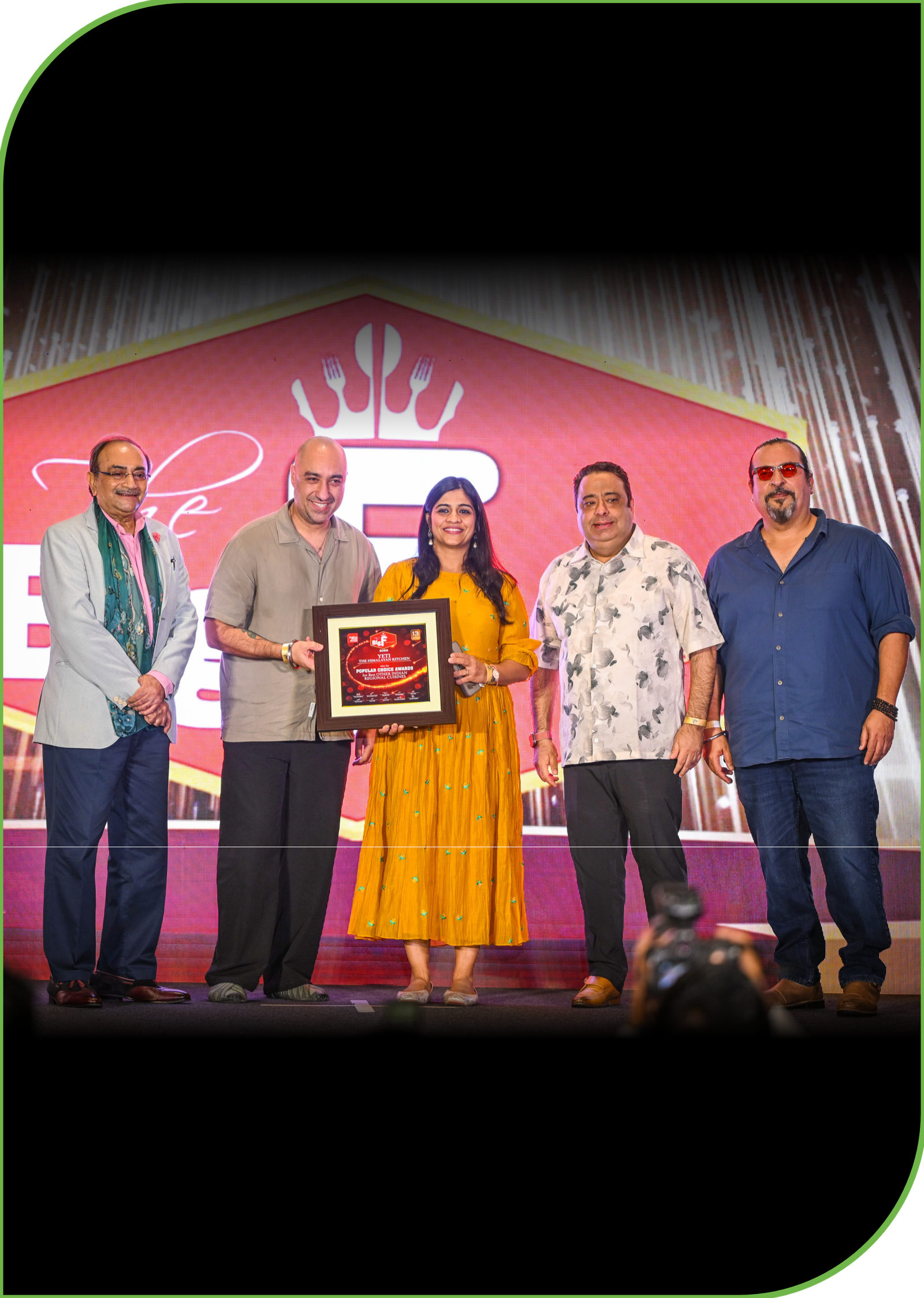 Yeti The Himalayan Kitchen_Awards_Big F Awards 2026 - Yeti Five people on a stage posing for a photo; woman in a yellow dress holds a framed award while four men stand beside her.